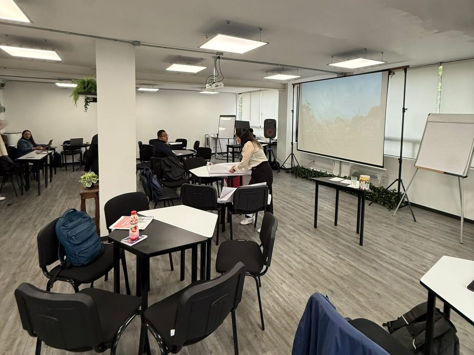 Sala de la Sede Insurgentes durante un taller: mesas de trabajo, proyector y pantalla